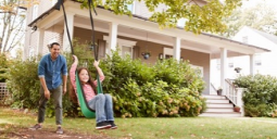 Dad Pushing Daughter On Swing In Front Of Family Home